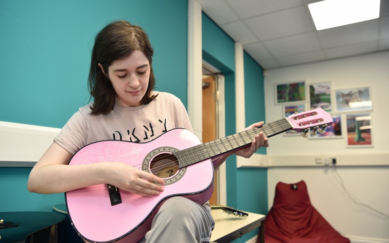 A participant playing guitar at a chill out session