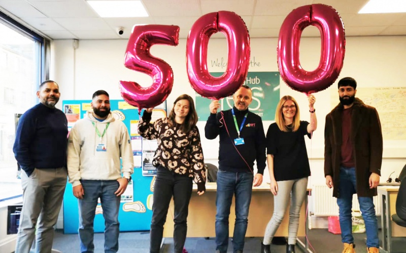 Colleagues at the Hub with balloons that spell out 500.