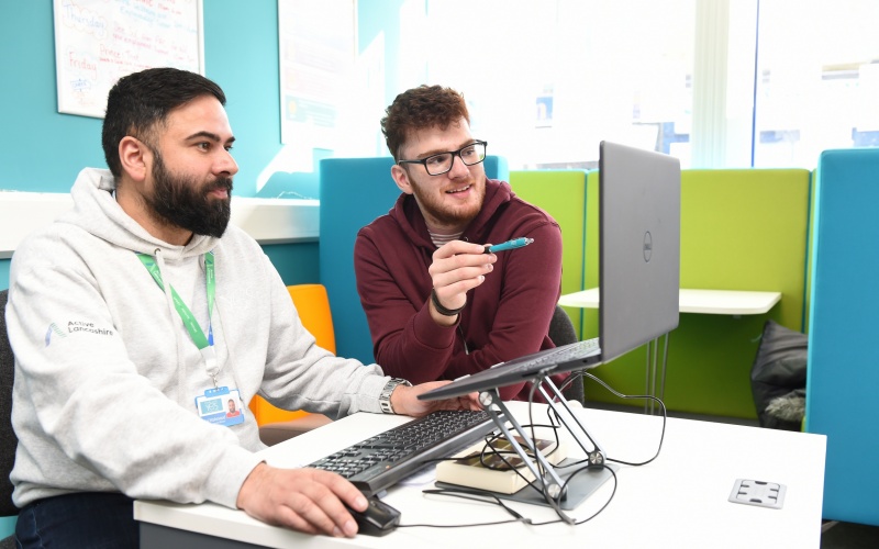 From left, Maj (Pendle YES Hub) sits at a computer with Adnan, who is quoted in the article.